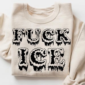 Pu&ograve; includere: Felpa color crema con la scritta "FUCK ICE" in un font nero gocciolante. Il disegno &egrave; centrato sulla parte anteriore del capo. Le maniche sono arrotolate. Farfalle rosa e un'illustrazione di una scatola sullo sfondo.