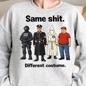 May include: A light gray sweatshirt with the text "Same shit. Different costume." The graphic features four cartoon figures in different uniforms and outfits, including a person in a black uniform with "ICE" on it.