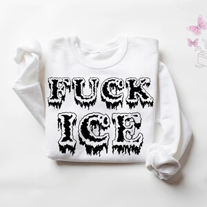 Pu&ograve; includere: Felpa bianca con la scritta "FUCK ICE" in grandi lettere nere gocciolanti. La parte superiore a maniche lunghe &egrave; stesa, con il testo ben visibile sul petto. Farfalle rosa e una grafica a scatola sullo sfondo.