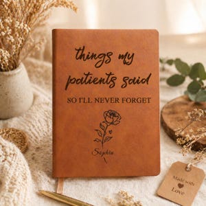 Op de afbeelding: Een bruin leren notitieboek met de tekst "things my patients said, so I'll never forget." Een rozenillustratie en de naam "Sophia" staan eronder. Een roze lint-bladwijzer is zichtbaar.