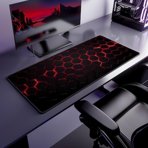 May include: A black and red gaming mouse mat featuring a honeycomb design. The mat is rectangular and covers a large area of the desk. The honeycomb cells glow red, creating a striking visual effect. A computer monitor and PC tower are visible in the background.