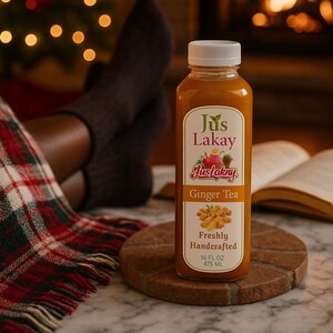 Peut inclure: Une bouteille transparente de Jus Lakay Ginger Tea avec un bouchon blanc, pos&eacute;e sur un dessous de verre en bois. L'&eacute;tiquette pr&eacute;sente du texte et des illustrations de gingembre et de fruits. La bouteille contient 475 ml de th&eacute;.