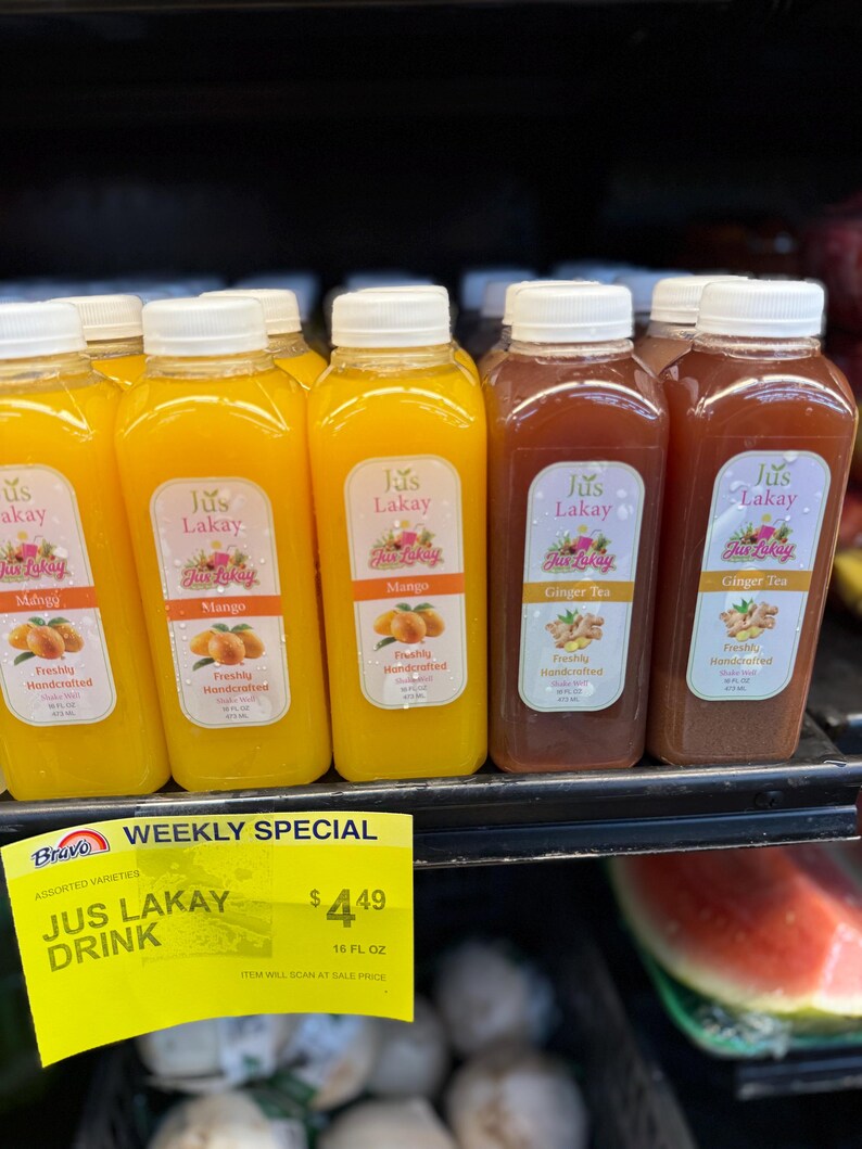 Peut inclure: Plusieurs bouteilles de Jus Lakay, saveurs mangue et th&eacute; au gingembre. Le jus de mangue est jaune vif, tandis que le th&eacute; au gingembre est brun rouge&acirc;tre. Chaque bouteille a un bouchon blanc et une &eacute;tiquette avec le nom de la marque et des illustrations de fruits.