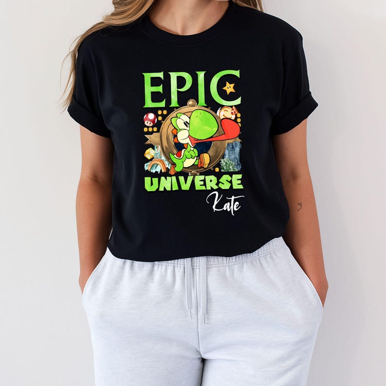 May include: Black t-shirt featuring a green Yoshi character with a long red tongue, surrounded by a gold-colored frame. The words "EPIC UNIVERSE" are in green, with "Kate" in cursive below the graphic.