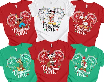 May include: A collection of red, white, and green t-shirts featuring Disney characters. Each shirt has a unique design with the text "Christmas Crew" and a character's name. The shirts are decorated with Christmas lights.