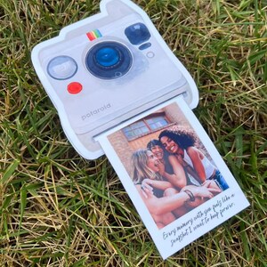 May include: A white Polaroid-style photo card with a picture of three women. The card has a rainbow stripe and the word "Polaroid" printed on it. The photo reads "Every memory with you feels like a snapshot I want to keep forever."