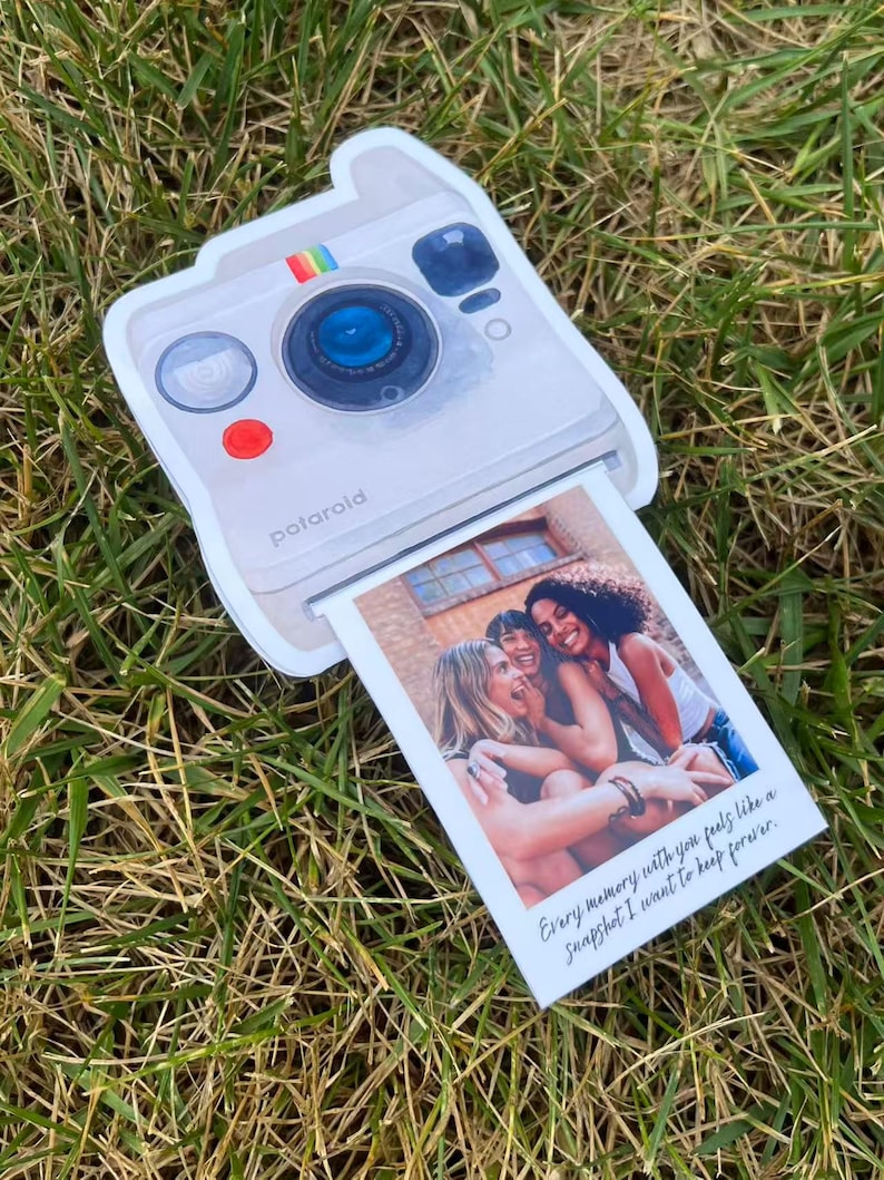 May include: A white Polaroid-style photo card with a picture of three women. The card has a rainbow stripe and the word "Polaroid" printed on it. The photo reads "Every memory with you feels like a snapshot I want to keep forever."