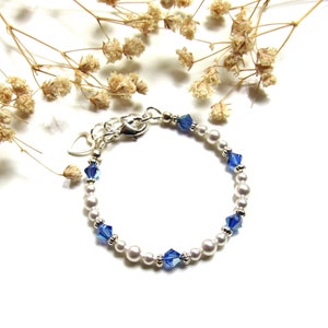 May include: A white pearl bracelet with blue crystal accents. The bracelet has a silver clasp.
