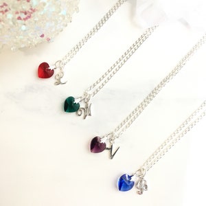 May include: Four silver necklaces with different colored crystal heart charms and letter pendants. The charms are red, green, purple, and blue.