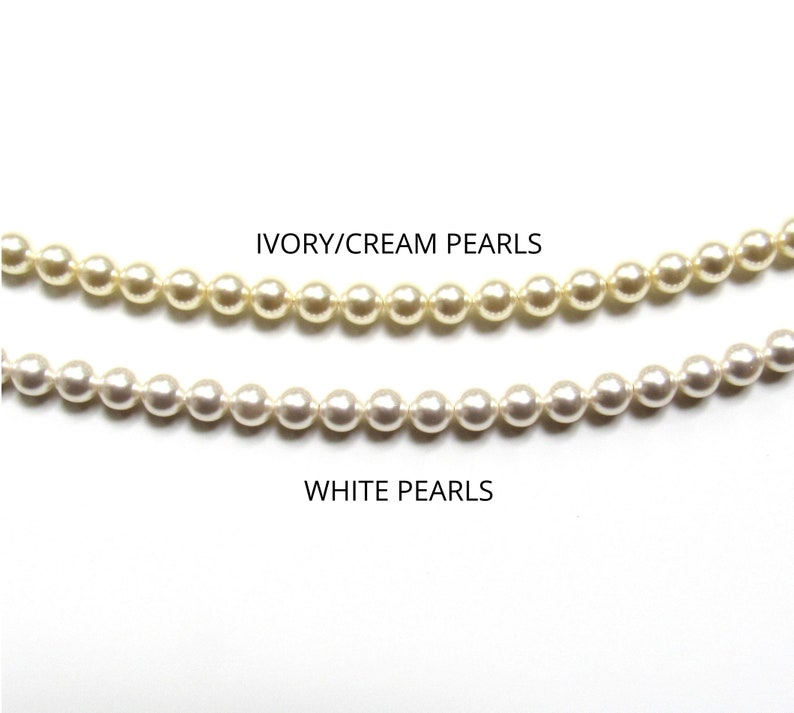 May include: Two strands of pearls, one strand is ivory/cream colored and the other strand is white. The text "IVORY/CREAM PEARLS" is above the ivory/cream strand and the text "WHITE PEARLS" is below the white strand.