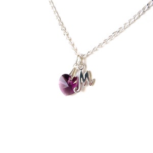 May include: A silver chain necklace with a purple heart charm and a silver letter 'M' charm.