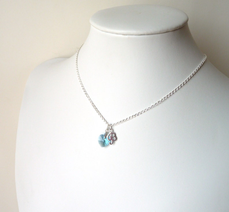 May include: A silver chain necklace with a light blue crystal and a silver flower charm.