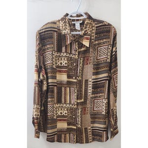 May include: A long-sleeve button-down shirt featuring a patchwork-style pattern in shades of brown, tan, cream, and black. The design includes various geometric shapes, stripes, and intricate motifs across the fabric, with a standard collar.