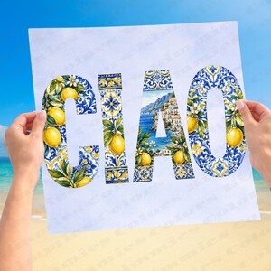 May include: A white paper with the word "CIAO" in large letters, held by two hands. The letters are decorated with yellow lemons, blue and white floral patterns, and a coastal town scene. The background shows a beach and blue sky.
