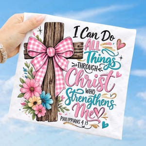 May include: White square fabric with a wooden cross, a pink gingham bow, and colorful flowers. The text reads "I Can Do All Things Through Christ Who Strengthens Me" from Philippians 4:13.