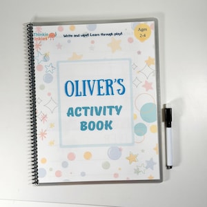 May include: A spiral-bound activity book for ages 2-4, titled "Oliver's Activity Book." The cover features colorful stars, planets, and bubbles, with the text "Write and wipe! Learn through play!" A black and white marker is included.