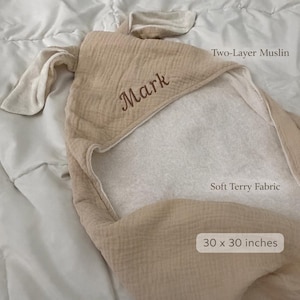 Peut inclure: Une serviette &agrave; capuche beige avec deux oreilles, portant le nom brod&eacute; Mark. La serviette est compos&eacute;e de mousseline double &eacute;paisseur avec un int&eacute;rieur en tissu &eacute;ponge doux, mesurant 76 x 76 cm. Elle pr&eacute;sente une capuche et un ext&eacute;rieur textur&eacute;.