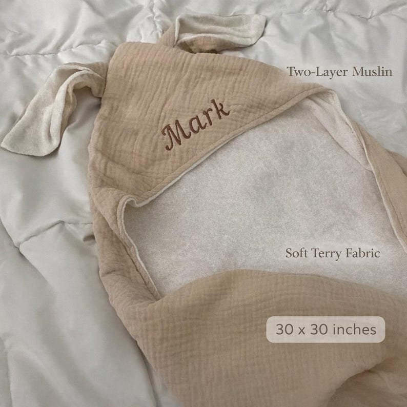 Peut inclure: Une serviette &agrave; capuche beige avec deux oreilles, portant le nom brod&eacute; Mark. La serviette est compos&eacute;e de mousseline double &eacute;paisseur avec un int&eacute;rieur en tissu &eacute;ponge doux, mesurant 76 x 76 cm. Elle pr&eacute;sente une capuche et un ext&eacute;rieur textur&eacute;.