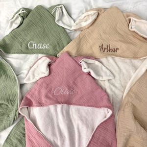 Peut inclure: Trois serviettes &agrave; capuche en vert sauge, beige et vieux rose, chacune dot&eacute;e d'oreilles d'animaux douces sur la capuche. La serviette vert sauge est brod&eacute;e du nom Chase, la beige avec Arthur et la vieux rose avec le nom Olivia.