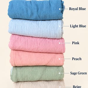 Peut inclure: Une pile de six &eacute;chantillons de tissu pli&eacute;s avec le texte COLOR OPTIONS, pr&eacute;sentant les couleurs suivantes de haut en bas : bleu royal, bleu clair, rose, p&ecirc;che, vert sauge et beige. Chaque tissu a une surface textur&eacute;e et froiss&eacute;e.