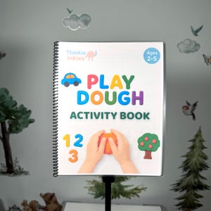 Puede incluir: Un "Play Dough Activity Book" encuadernado en espiral con texto e ilustraciones coloridas. La portada presenta un coche azul, las palabras "PLAY DOUGH ACTIVITY BOOK" y los números 1, 2 y 3. El libro está diseñado para niños de 2 a 5 años.