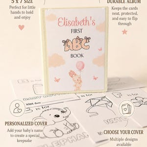 Può includere: Un libro ABC personalizzato di 13 x 18 cm per bambini con una copertina chiara che raffigura un coniglietto che tiene un palloncino rosa, nuvole e farfalle. Il testo sulla copertina recita Elisabeth's FIRST ABC BOOK. Diverse carte bianche con disegni a linee nere di oggetti come un biberon, un elefante e un aquilone sono mostrate in primo piano.