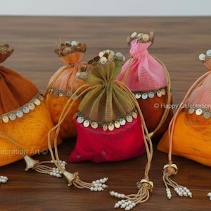 May include: A collection of five decorative drawstring pouches in various colors, including orange, pink, and green. Each pouch is adorned with sequins and a beaded tassel, perfect for small gifts or favors.
