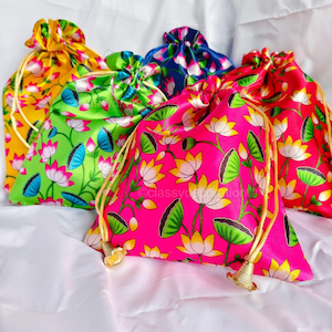 Puede incluir: Una colección de bolsas con cordón en varios colores: amarillo, verde, azul, rosa y rojo. Cada bolsa está adornada con un estampado floral con flores de loto blancas y amarillas y hojas verdes. Las bolsas son de tela brillante.