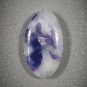 May include: Oval shaped cabochon gemstone with a white base and purple swirls.