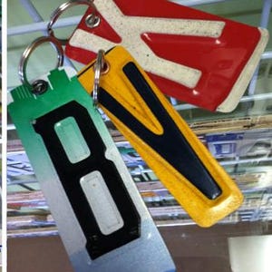 K&ouml;nnte beinhalten: Drei Schl&uuml;sselanh&auml;nger mit Buchstabenanh&auml;ngern. Der erste Schl&uuml;sselanh&auml;nger ist rot mit einem wei&szlig;en Buchstaben "X". Der zweite Schl&uuml;sselanh&auml;nger ist gelb mit einem schwarzen Buchstaben "V". Der dritte Schl&uuml;sselanh&auml;nger ist gr&uuml;n, blau und wei&szlig; mit einem schwarzen Buchstaben "B".