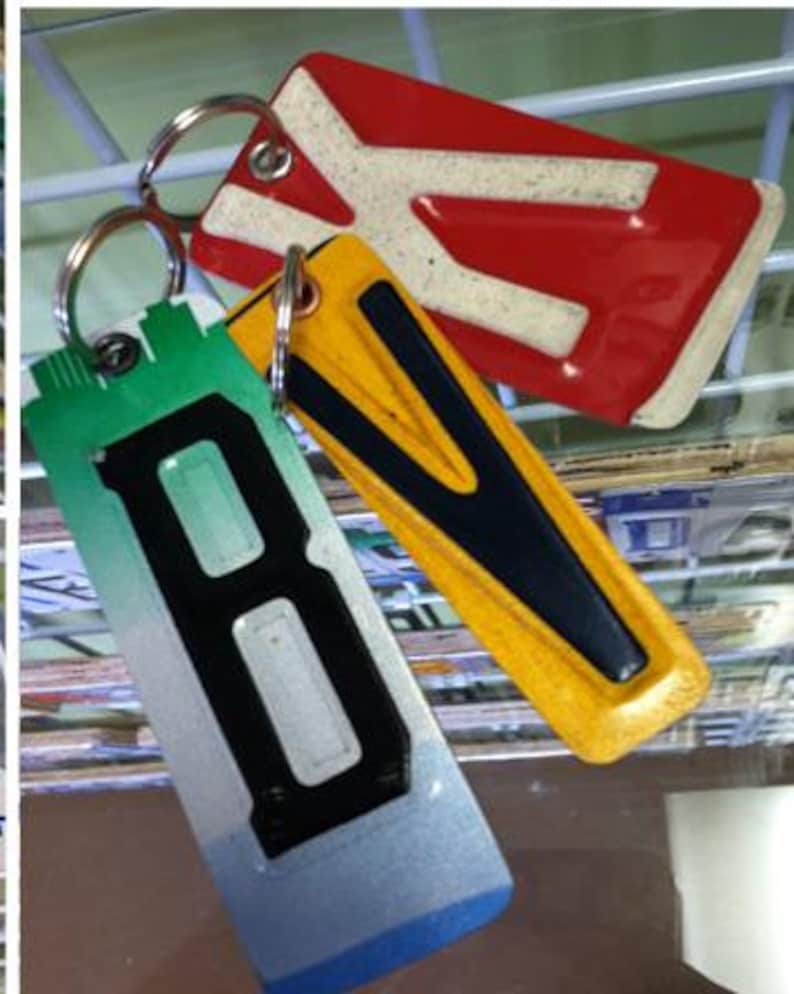 K&ouml;nnte beinhalten: Drei Schl&uuml;sselanh&auml;nger mit Buchstabenanh&auml;ngern. Der erste Schl&uuml;sselanh&auml;nger ist rot mit einem wei&szlig;en Buchstaben "X". Der zweite Schl&uuml;sselanh&auml;nger ist gelb mit einem schwarzen Buchstaben "V". Der dritte Schl&uuml;sselanh&auml;nger ist gr&uuml;n, blau und wei&szlig; mit einem schwarzen Buchstaben "B".