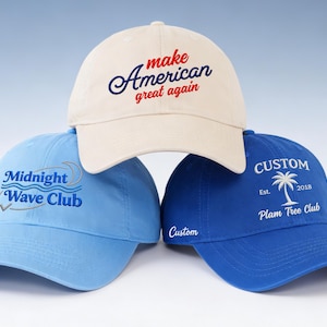 May include: Three baseball caps in light blue, cream, and royal blue. The cream cap has the text "make American great again". The light blue cap says "Midnight Wave Club". The royal blue cap says "Custom Plam Tree Club".