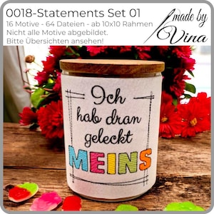 Może przedstawiać: Szklany słoik z drewnianą pokrywką i białą tkaniną z kolorowym haftem "Ich hab dran geleckt MEINS". Słoik stoi na tle czerwonych kwiatów i drewnianej powierzchni.