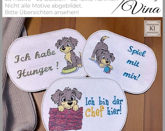 以下が含まれることがあります： ドイツ語のテキストが入った、犬をテーマにした刺繍パッチ。パッチの1つは「Ich habe Hunger!」（お腹すいた！）、別のパッチは「Spiel mit mir!」（遊んで！）、3つ目は「Ich bin der Chef hier!」（私がボスだ！）と書かれています。