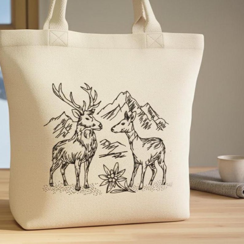 Helle Canvas-Einkaufstasche mit gesticktem Hirsch- und Reh-Motiv vor Bergsilhouette auf einem Holztisch.

Light canvas tote bag with an embroidered stag and deer motif in front of a mountain silhouette.
