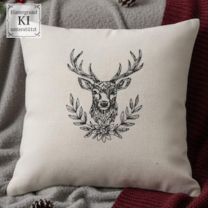 Cremefarbenes Kissen mit gesticktem Hirschkopf im Kranz, gemütlich dekoriert mit einer grauen Decke.

Cream-colored cushion with an embroidered stag head in a wreath, cozy with a grey blanket.