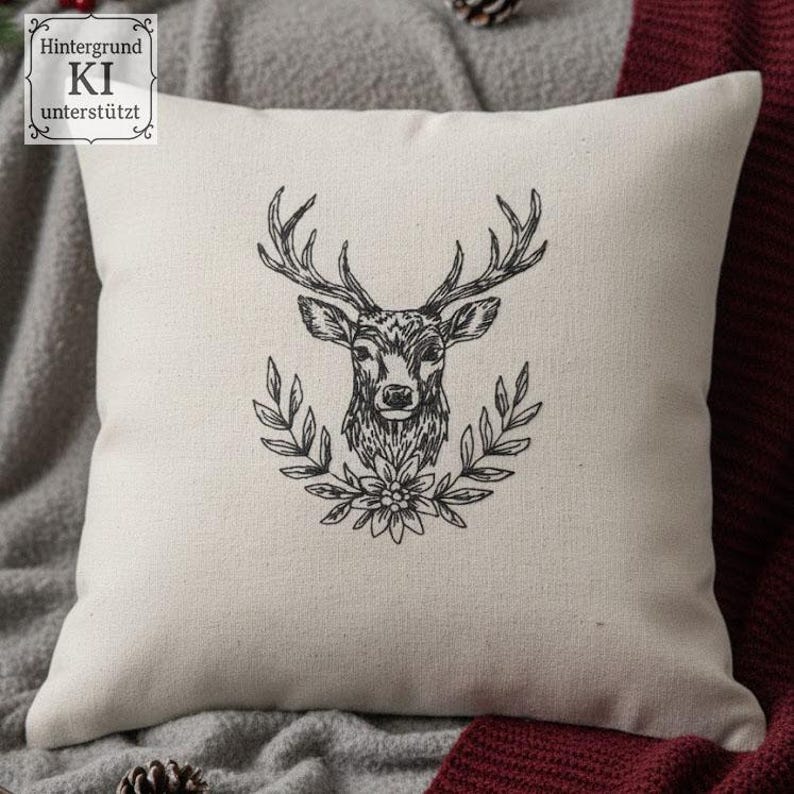 Cremefarbenes Kissen mit gesticktem Hirschkopf im Kranz, gemütlich dekoriert mit einer grauen Decke.

Cream-colored cushion with an embroidered stag head in a wreath, cozy with a grey blanket.