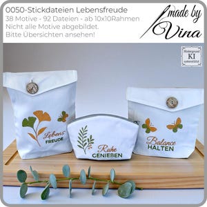 Può includere: Tre sacchetti di stoffa bianca e un astuccio con cerniera con disegni ricamati. I sacchetti presentano motivi botanici e farfalle con testo in tedesco. I sacchetti sono chiusi con bottoni di legno. Il testo include le parole "Lebensfreude", "Ruhe" e "Balance halten".