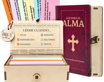 Könnte beinhalten: Eine Holzkiste mit Scharnierdeckel, die farbige Karten und ein kleines Holzschild mit der Aufschrift "Para Ti" enthält. Ein weinrotes Buch mit den Worten "Luz Para El Alma" und einem Kreuz befindet sich neben der Kiste. Auf der Kiste steht "LÉEME CUANDO...".