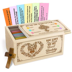 Op de afbeelding: Een houten kist met een scharnierend deksel, met kleurgecodeerde bijbelverzen. De kist is versierd met een hartvormige bloemenkrans en een afbeelding van een Duitse herder. De tekst "YOU LEFT Paw Prints ON MY Heart Buddy 2019-2025" is zichtbaar.