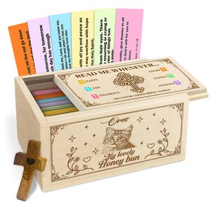 Könnte beinhalten: Eine Holzkiste mit Scharnierdeckel, die farbige Karten mit Bibelversen enthält. Die Kiste ist mit einer Katzenillustration und dem Text "My lovely Honey bun" verziert. Ein Holzkreuz ist ebenfalls vorhanden.