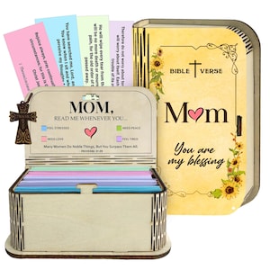 May include: A wooden Bible verse box with a cross-shaped charm. The box is open, revealing colourful cards with Bible verses. The lid features the words "Bible Verse" and "Mom, You are my blessing" with sunflower accents.