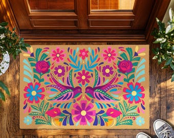 Può includere: Un zerbino rettangolare con un vivace design floreale e di uccelli. Il tappeto presenta uno sfondo beige con fiori colorati, foglie e due uccelli simmetrici. I fiori sono rosa, viola, blu e gialli. Gli uccelli sono viola e turchese.