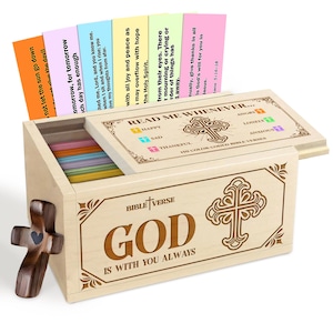 Op de afbeelding: Een houten kist met de tekst "GOD IS WITH YOU ALWAYS" en een kruisontwerp. De kist bevat kleurrijke kaarten met bijbelverzen. Een houten kruis met een hart staat aan de zijkant. De kist is gelabeld "READ ME WHENEVER..."