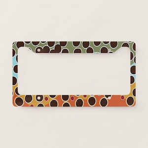 May include: License plate frame with a colorful pattern. The frame features a repeating design of brown circles on a background of blue, green, orange, and yellow. The frame is rectangular with rounded corners.