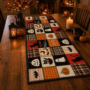 Op de afbeelding: Een rechthoekige tafelloper met een patchworkontwerp van vierkanten met Halloween-motieven, waaronder zwarte katten, witte geesten, oranje pompoenen, vleermuizen en skeletten, afgewisseld met ruit- en streepmotieven in oranje, zwart en wit.