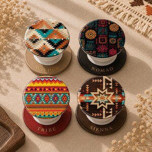 May include: Four round phone grips with colorful geometric patterns. Each grip has a different design and color scheme, including orange, teal, black, and brown. The bases are in various colors, with the words "WILDER", "NOMAD", "TRIBE", and "SIENNA" printed on them.