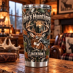 May include: A stainless steel tumbler featuring a wrap-around print of a deer with large antlers in a forest setting. The text He's Hunting is printed at the top, and the name JACKSON is displayed at the bottom within an antler graphic.