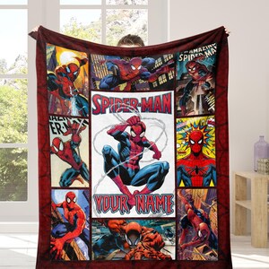 Op de afbeelding: Een bordeauxrode Spider-Man-deken met een collage van stripboekpanelen. Het centrale paneel toont Spider-Man met de tekst "YOUR NAME". De deken heeft een rode rand.