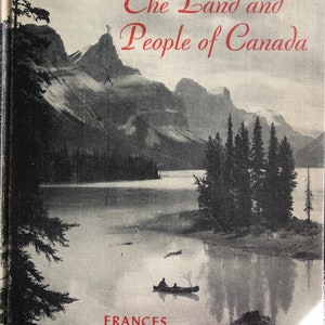 May include: Book cover with a black and white photo of a mountain lake with trees and a canoe. The title is "The Land and People of Canada" and the author is "Frances Aileen Ross".